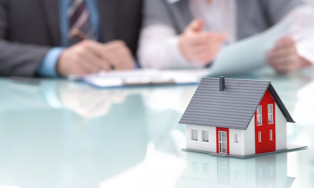 Businessman signs contract behind home architectural model