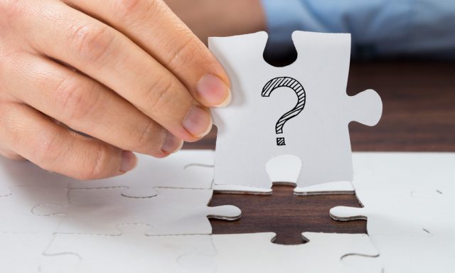 Close-up Of Person Hand Holding Puzzle With Question Mark Sign